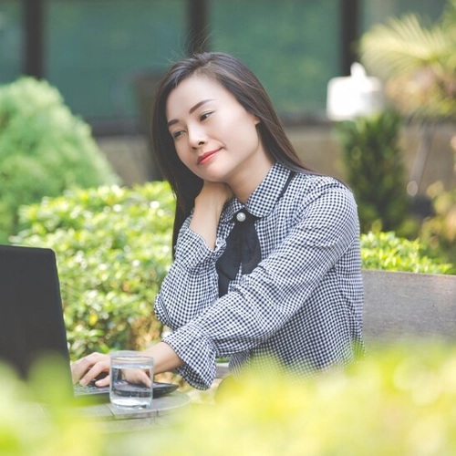Smiling person outdoors with laptop, illustrating NDIS capacity building, support coordination, and disability support services for independent living.