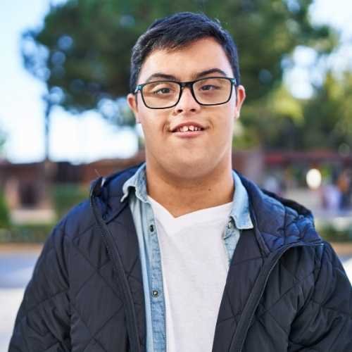 Young neurodiverse man, smiling. illustrating NDIS capacity building, support coordination, and disability support services for independent living.