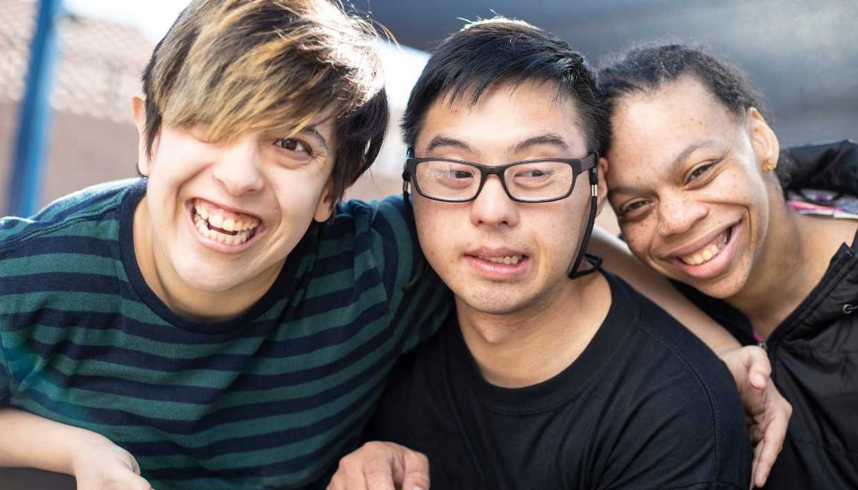 3 young people who are neurodiverse, looking at camera, smiling. Equine therapy near me, and holistic counselling for emotional well-being.